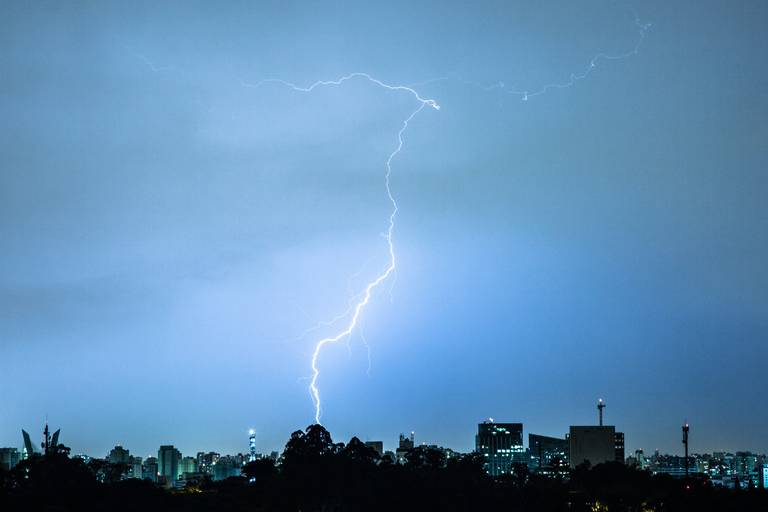 Fotografia de um raio iluminando um céu azul parcialmente nublado durante uma tempestade.