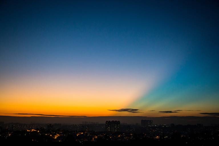 Vista panorâmica da cidade de São Paulo com um céu de outono em tons de azul e amarelo, com a luz do sol poente.