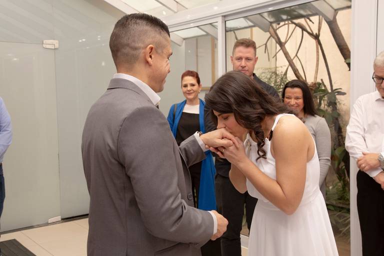 Noiva beijando a mão do noivo, retribuindo o carinho em um momento de afeto.
