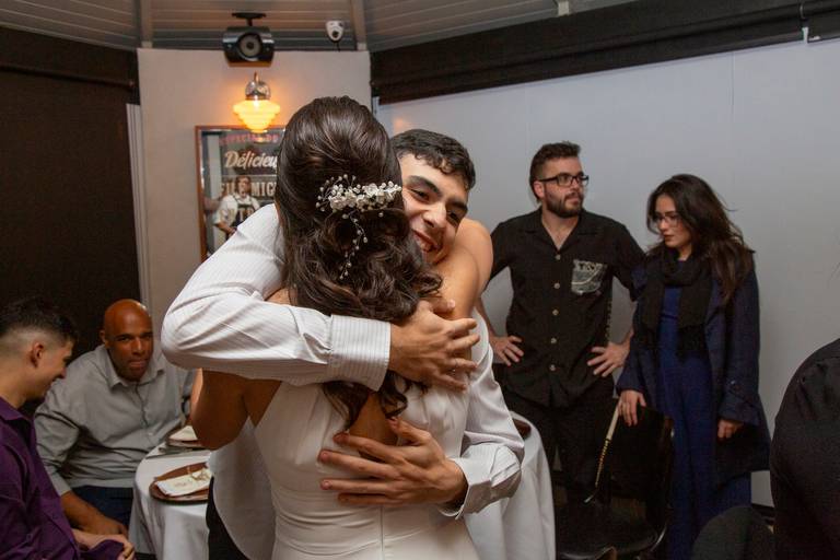 Noiva abraçando um convidado com um sorriso, em um momento de carinho e celebração na festa.