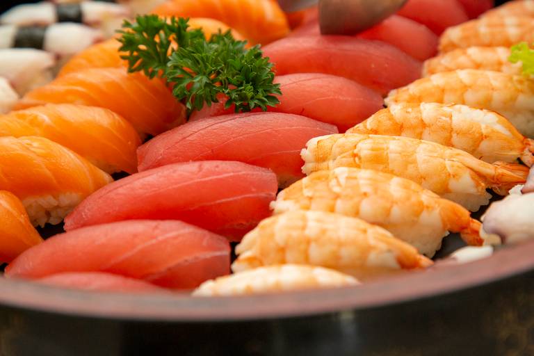 Pratos de comida japonesa, como sushi e sashimi, servidos em uma festividade.
