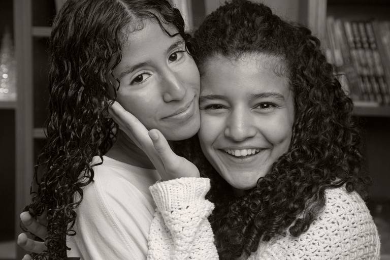 Duas filhas posando juntas para uma foto, mostrando a cumplicidade e a alegria entre irmãs.