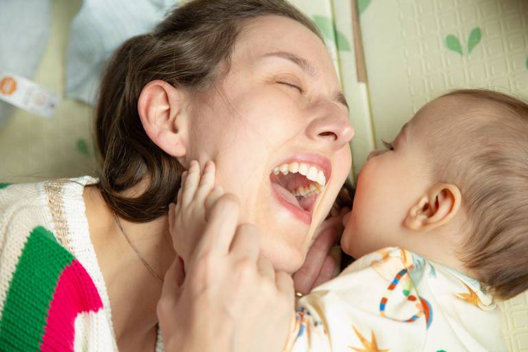 Mãe brincando com o bebê, em um momento de carinho e diversão.