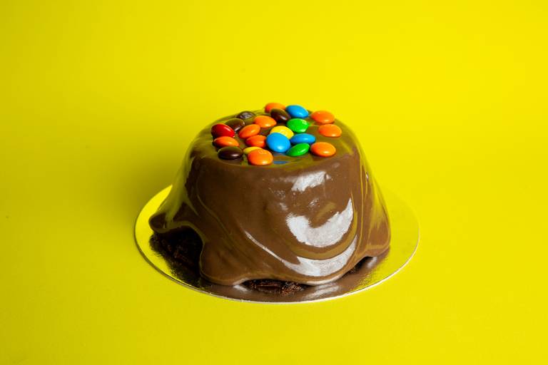 Fotografia gastronômica de mini bolo vulcão com cobertura de chocolate e M&Ms coloridos. Autoria de Bruno Arita