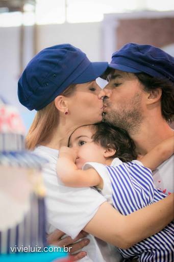 pais se beijando e filho deitado no colo deles