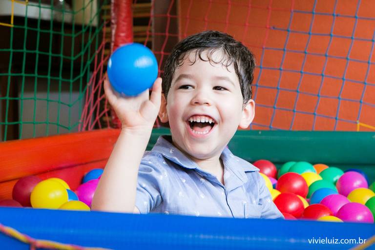 criança jogando bolinha na piscina de bolinhas