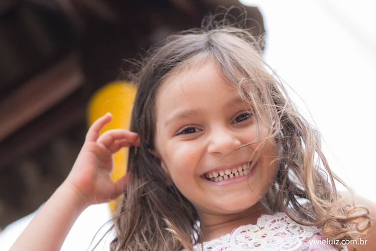 criança com a mao no cabelo sorrindo