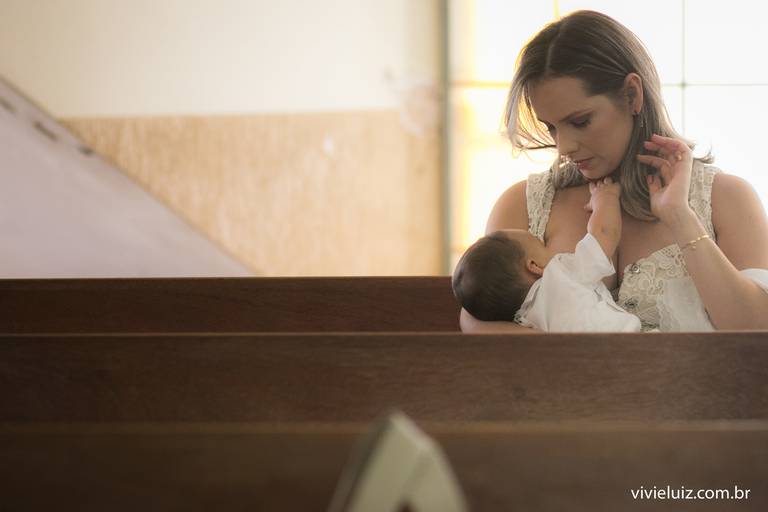mãe amamentando o filho antes do batizado