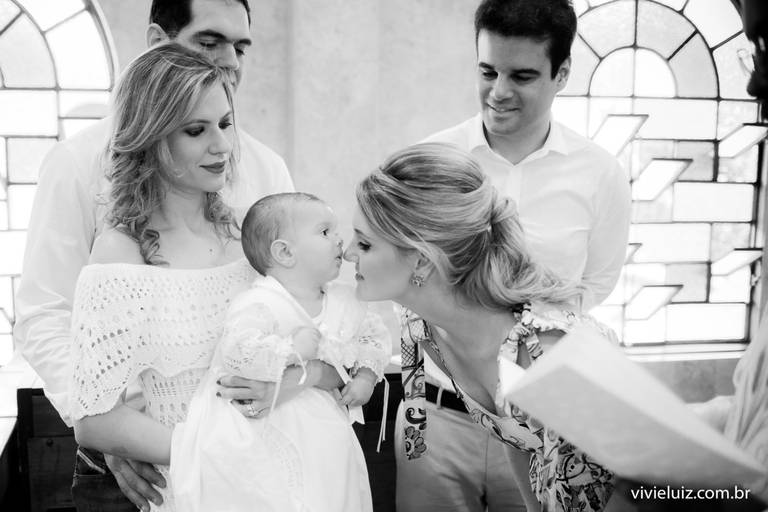 mãe dando um beijo no filho no dia do seu batismo