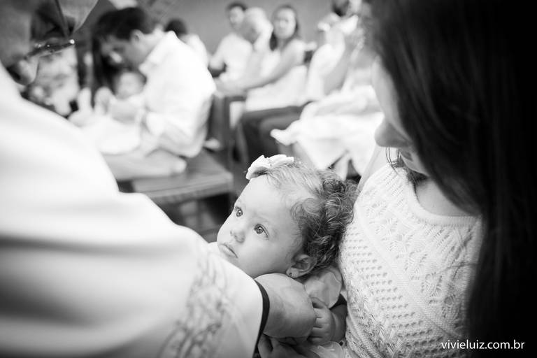 bebê olhando o padre no dia do seu batismo
