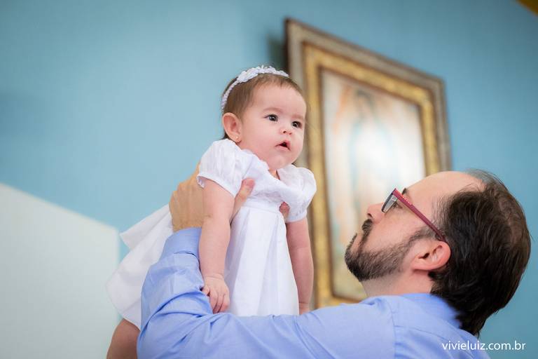 pai levantando a sua filha em frente a imagem de Nossa Senhora