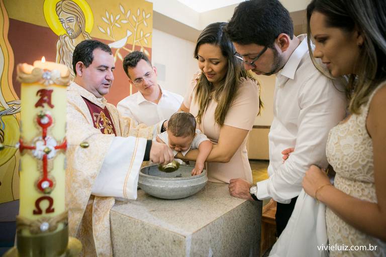 batizando o bebê, pais e padrinhos em volta