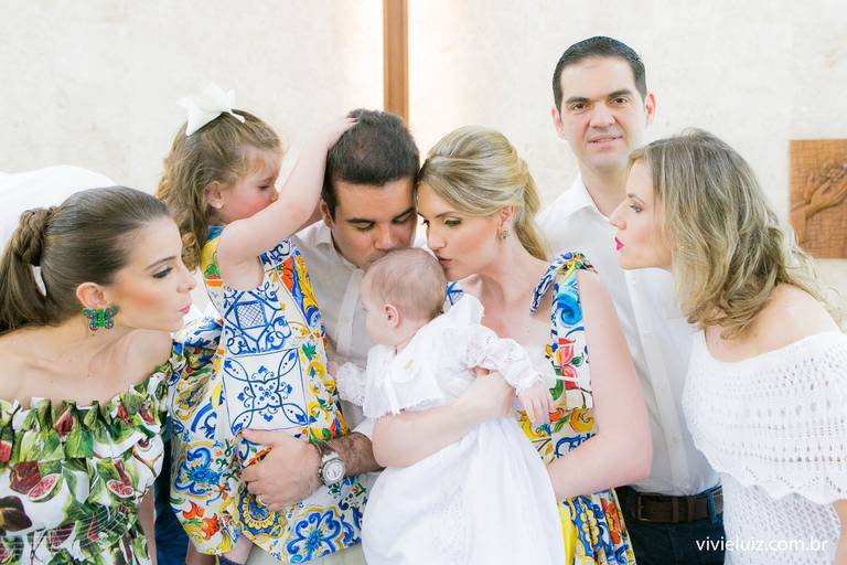 família dando beijo na bebê que foi batizada