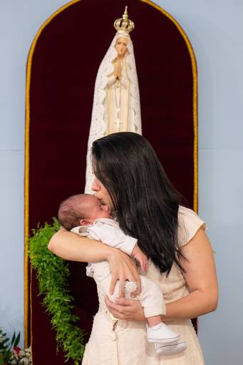 mãe dando um beijo no seu filho aos pés de Nossa Senhora