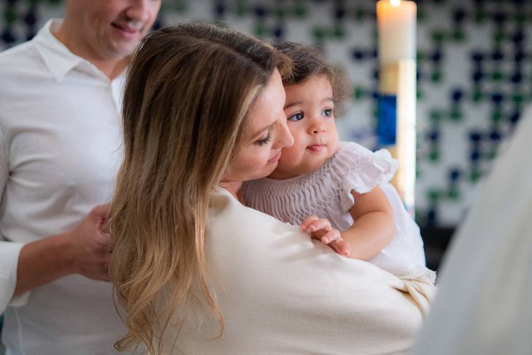 mãe segurando sua filha no batismo