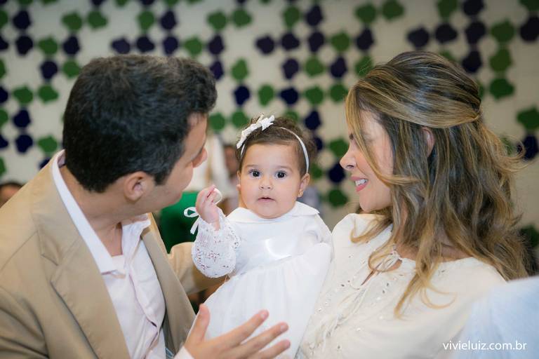 pais segurando a filha na hora do batismo