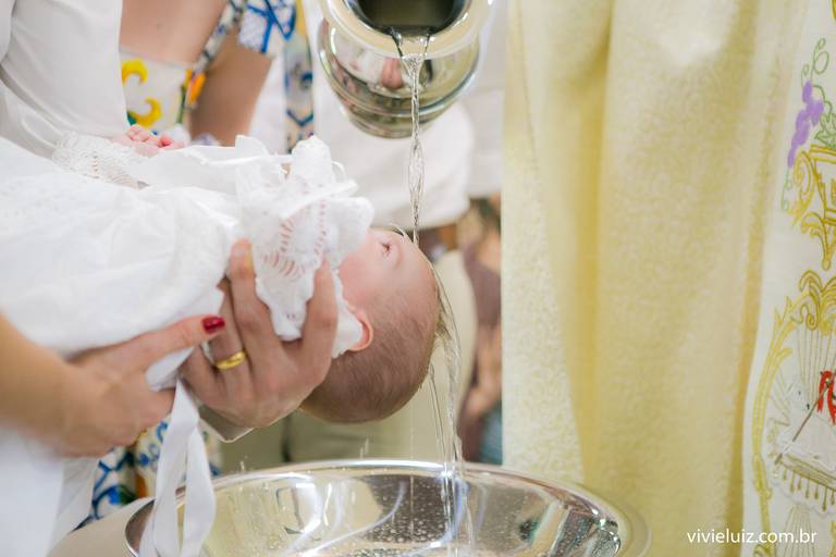 padre jogando água na cabeça do bebê e o batizando