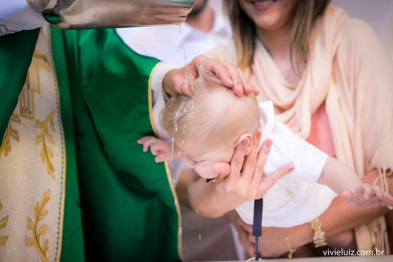 padre jogando água na cabeça do bebê e o batizando