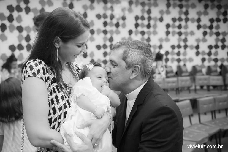 padre dando um beijo na criança que foi batizada