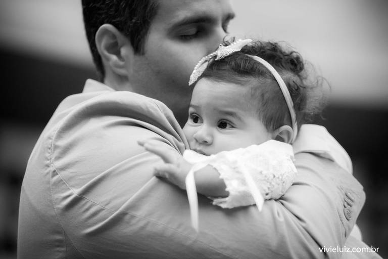 pai abraçando e beijando a sua filha que foi batizada