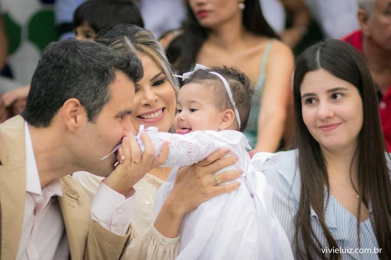 pai dando beijo na mão da filha que está no colo da mãe