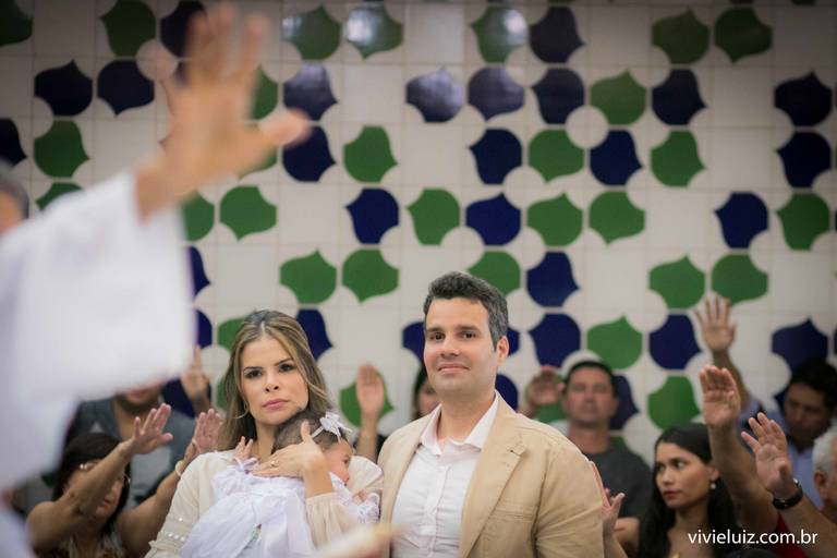 família reunida para o batizado enquanto o padre dá uma palavra