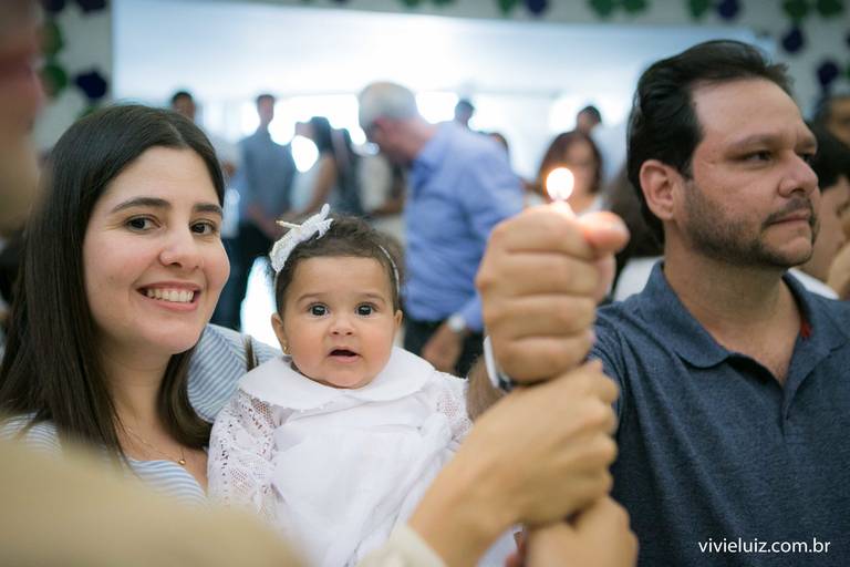padrinhos com a afilhada de batismo segurando uma vela 