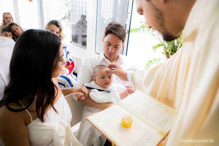 padre ungindo o bebê com o óleo batismal