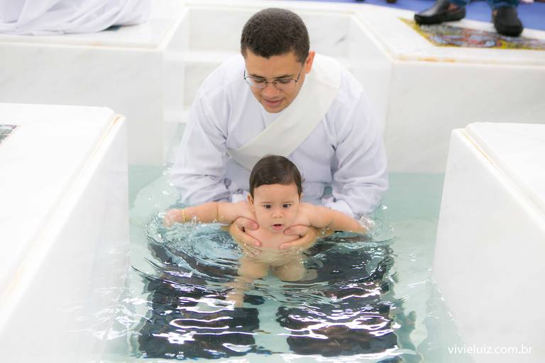 padre batizando o bebê na pia batismal