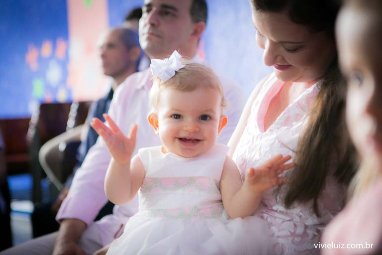 criança rindo no colo da mãe no seu batismo