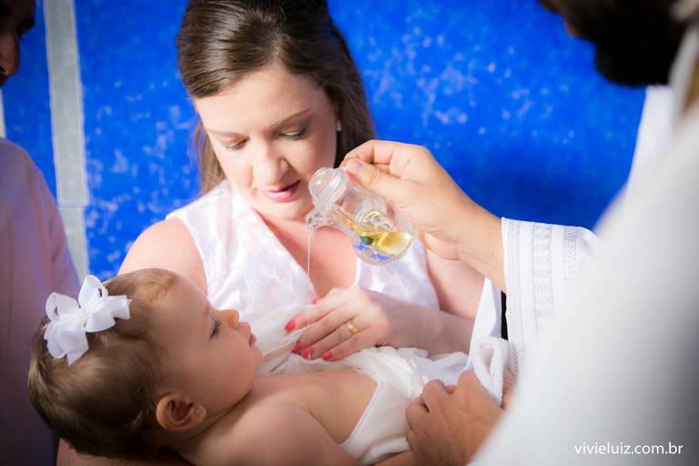 padre ungindo o óleo batismal na bebê