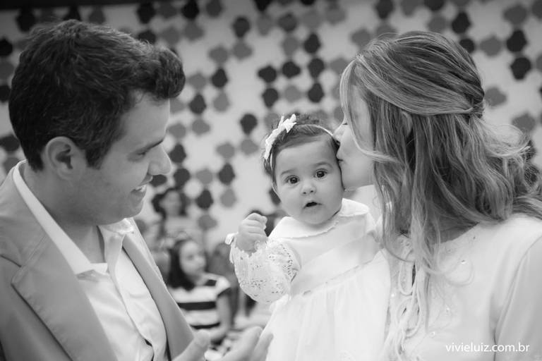 mãe dando um beijo na filha que foi batizada