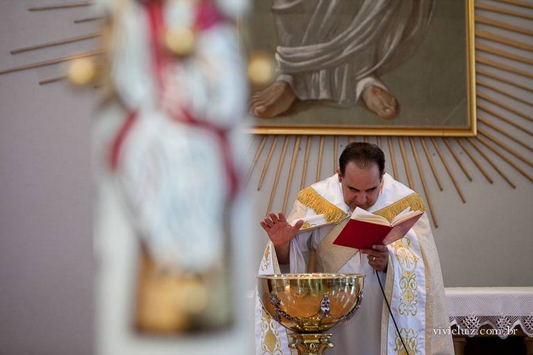 padre abençoando a água na pia batismal