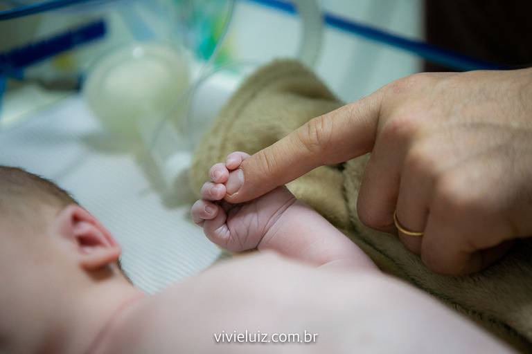 Mão do bebê segurando o dedo do papai