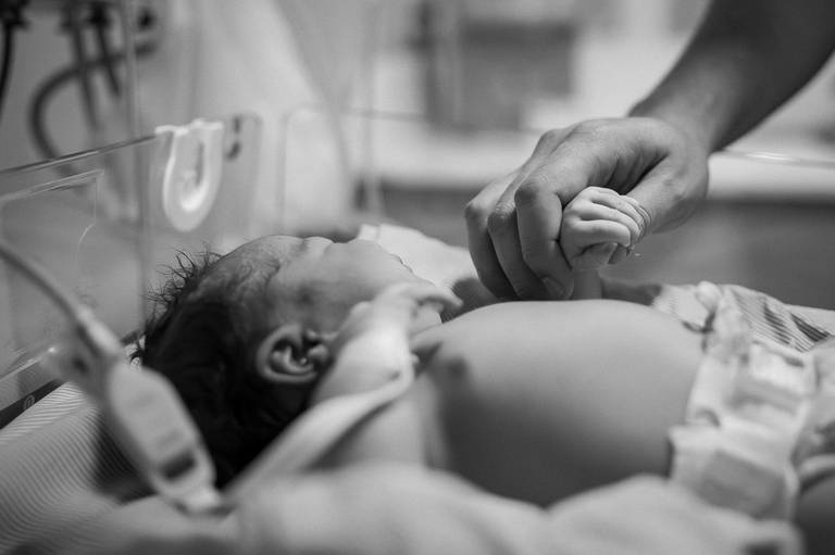 pai segurando a mão do seu filho recém nascido