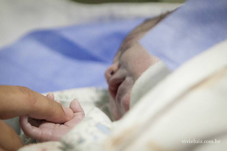 pai segurando a mão do seu filho recém nascido