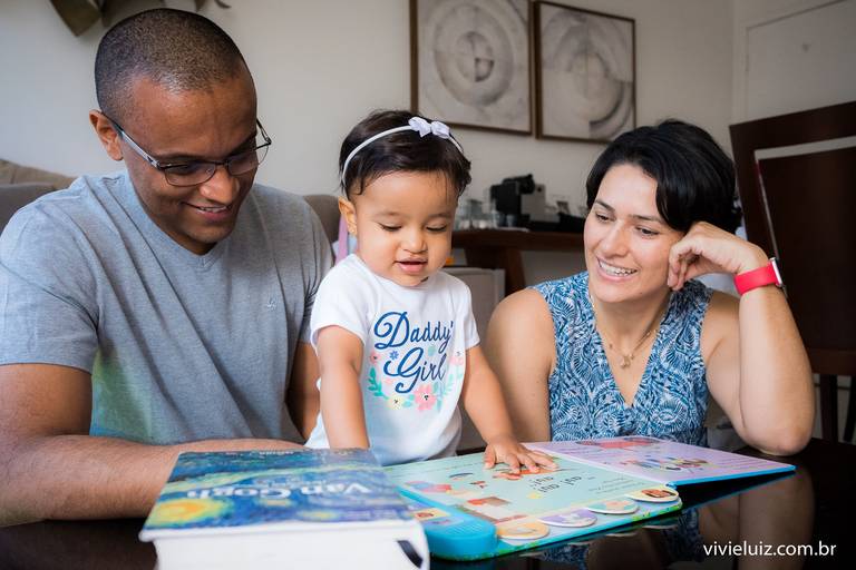 família lendo livros com a bebê