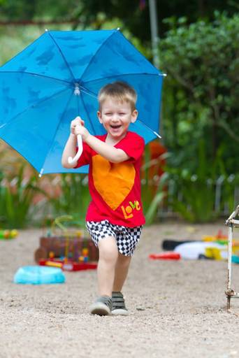 criança corredno com um guada chuva
