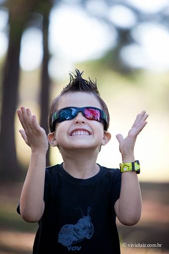 criança sorrindo de óculos escuros