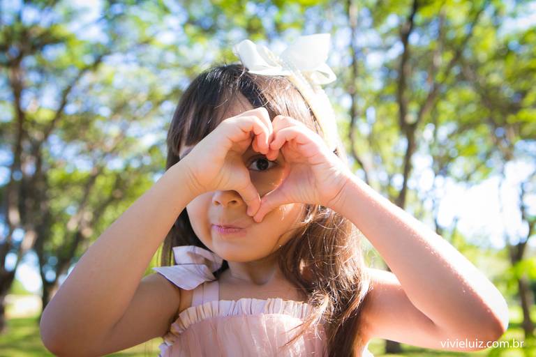 menina fazendo um coração com as mãos
