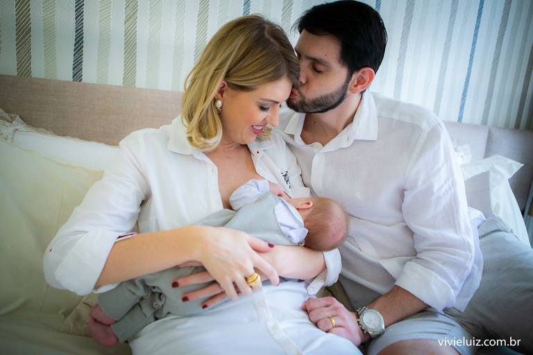 mãe amamentando o filho e pai dando um beijo na esposa