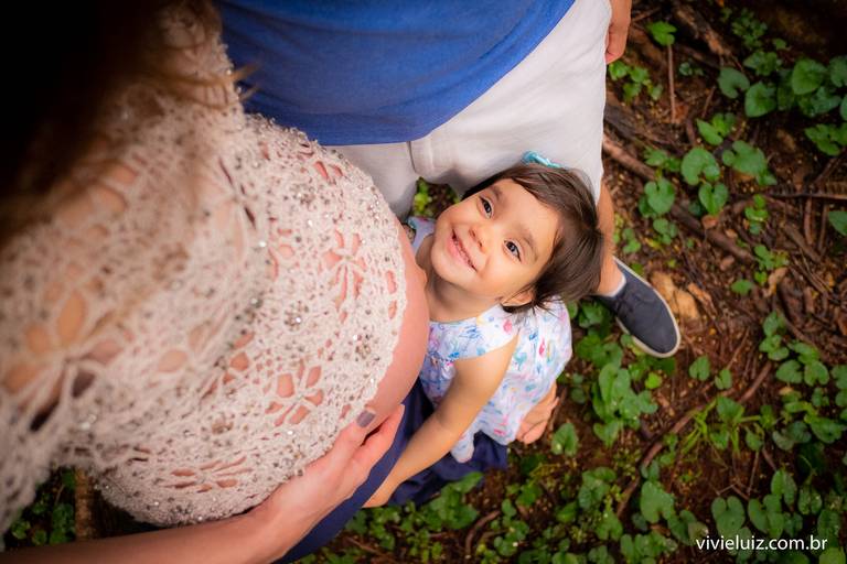 filha olhando para a barriga de grávida da mãe