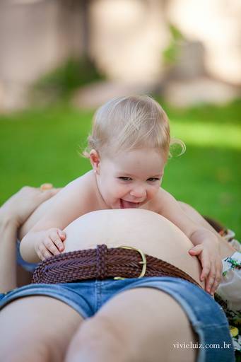 bebê dando beijo na barriga grávida da mãe