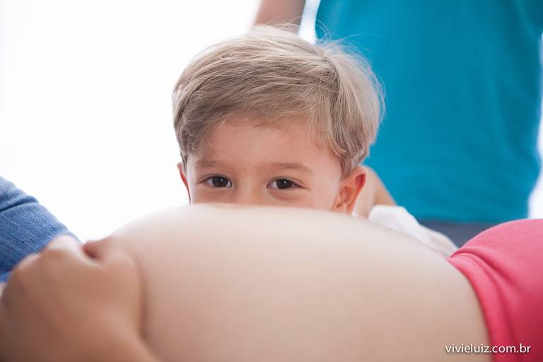 criança olhando a barriga grávida da mãe