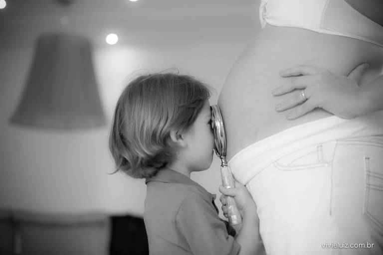 criança olhando com uma lupa a barriga da mamãe grávida
