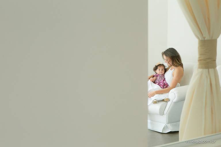 mãe segurando a filha no colo dentro do quarto