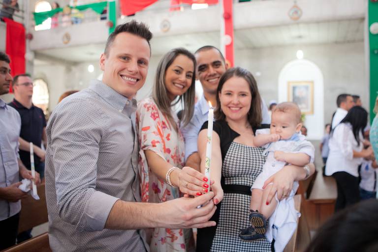 pais, padrinhos e criança segurando a vela durante batizado na Paróquia São José, Osasco, São Paulo