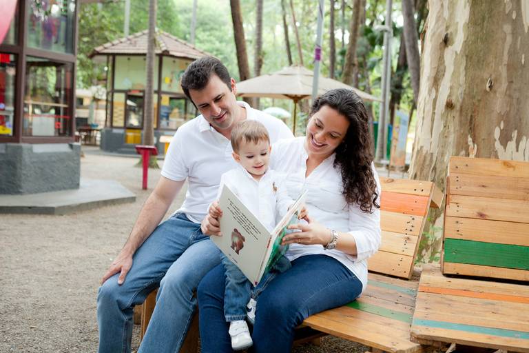menino lendo livro com os pais durante ensaio de família no Parque Da Agua Branca, Pompéia, Zona Oeste, São Paulo