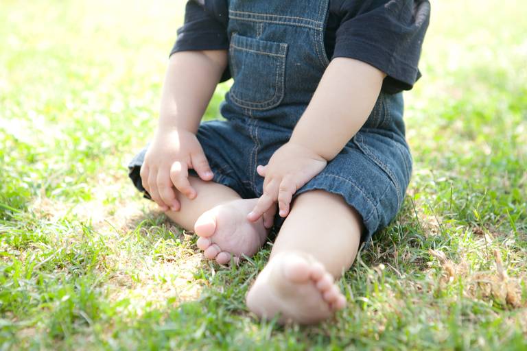 bebê segurando o pé sentado na grama durante ensaio de família no Parque Villa Lobos, Pinheiros, Zona Oeste, São Paulo