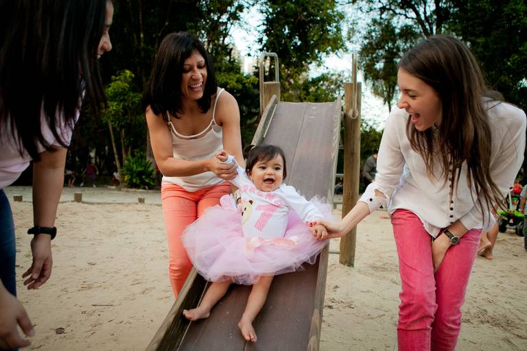mãe e irmãs brincando com menina no escorregador  durante ensaio de família no parque em Barueri, Alphaville, São Paulo